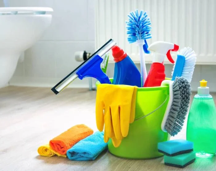 Bucket of cleaning products with gloves, cloths, brushes and a window squeegee