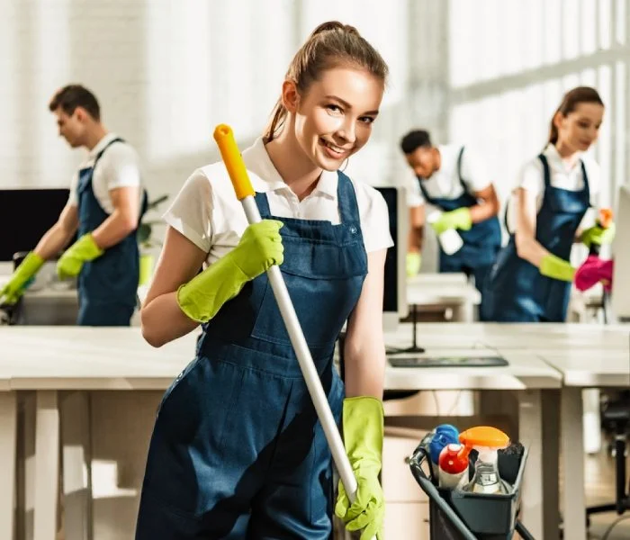 Commercial cleaning staff mopping an office floor and wiping workstations